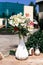 A multi-colored orchid in a white vase on a table in a street cafe. Summer background.