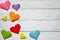 Multi-colored origami paper hearts on a white wooden background.