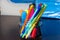 Multi-colored pens and markers in a stand on the background of Stack of Notebooks.  Pack of blue school notebooks on the table