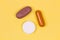 Multi-colored pills on a yellow background. Colorful medicines of different shapes on a bright backdrop. A group of antibiotics