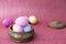 Multi-colored purple, pink, blue, yellow Easter eggs in a carved ceramic box on a pink shiny bokeh background. Symbol of