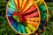 Multi colored round pinwheel in motion, in sunny garden. Big round rainbow pinwheel in motion.