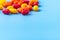 Multi-colored shiny dragees with fillings of orange, wild berries, lemon are scattered on a blue background. The view from the top