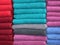 Multi-colored towels on a store shelf. Different towels are evenly folded