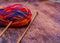 Multi coloured ball of knitting yarn and bamboo needles on a wooden background