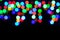 Multi-coloured de-focused lights against black background. Festive background. Defocused