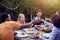 Multi-Cultural Friends At Home Around Table Making A Toast As They Enjoy Food At Summer Garden Party