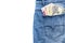 Multi currency banknotes in back pocket of blue jeans on white background