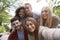 Multi ethnic group of five young adult friends pose to camera while taking a selfie during a break in a hike