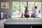 Multi ethnic group of four young adult friends celebrating at a dinner party raising their wine glasses, seen from kitchen island