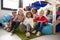 A multi-ethnic group of infant school children sitting on bean bags in a comfortable corner of the classroom, smiling to camera, l