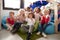 A multi-ethnic group of infant school children sitting on bean bags in a comfortable corner of the classroom, smiling and waving t
