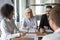 Multi-ethnic smiling office workers chatting at briefing in boardroom