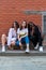Multi ethnic stylish portrait of young girls in casual clothes that crouched and looking at the camera isolaed over red