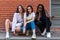 Multi ethnic stylish portrait of young girls in casual clothes that crouched and looking at the camera isolaed over red
