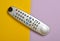 Multi-function push-button TV remote control on a colored pastel background. Top view