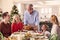 Multi-Generation Family Celebrating Christmas At Home With Grandfather Serving Turkey