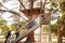 Multi-Generation Family Climbing Outdoor Wooden Platform To Tree House In Garden