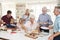 Multi-Generation Family And Friends Eating Food In Kitchen At Celebration Party