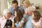 Multi Generation Family Group Sitting On Sofa Indoors