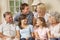 Multi Generation Family Group Sitting On Sofa Indoors