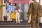 Multi-Generation Family With Parents And Wife Welcoming Army Soldier Home On Leave With Banner