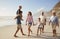 Multi Generation Family On Vacation Walking Along Beach Together