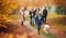 Multi-Generation Family Walking With Pet Golden Retriever Dog Along Autumn Woodland Path