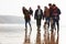 Multi Generation Family Walking On Winter Beach With Dog