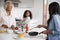 Multi Generation Female Family In Kitchen At Home Making Pancakes Together