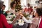 Multi generation mixed race family sitting at Christmas dinner table holding hands and saying grace, selective focus, close up