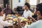 Multi-generational African-American family saying grace at dinner table and holding hands