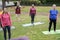 Multi generational people doing yoga class at city park - Main focus on african woman face