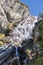 Multi-level alpine streams of Lillaz waterfall Cascate di Lillaz wash around granite karst rapids of rock under blue sky