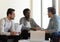 Multi-racial businessmen negotiating seated on couch in office