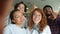 Multi-racial group of young people taking selfie in college library smiling