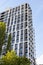 Multi-storey building against the blue sky. Tall new building with mirrored windows, bottom view. Background texture: high-rise,