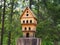 Multi-storey wooden carved birdhouse on a tree stump, a feeder for birds in the park