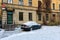 At the multi-storey yellow house on the roadside parked snow-covered car.