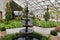 Multi-tiered black fountain inside of botanical gardens with glass roof