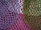 The multicolor background of the zero waste string bags, closeup of the knitted net. Selective focus