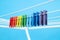 Multicolor clothespins hanging on drying rack on blue background