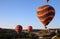Multicolor hot air balloons on clear sunlit sky and rocks