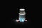 Multicolor pills around a white pill bottle. Jar of medicine. Black background.