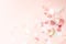 Multicolor pink, gold and white confetti falling on the pastel light pink background, holiday celebration backdrop