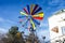 Multicolor small windmill by blue sky near house