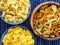 Multicolor spiral macaroni Wooden white and glass bowl with pasta on a textured blue white striped background, close-up