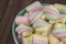 Multicolor spiral marshmallows bowl on wooden table, close-up background. Sweet airy dessert, spiral shape, color yellow pink