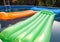 Multicolored air mattresses floating on the calm surface of a smaller pool