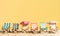 Multicolored beach chairs on a sunny sand beach over yellow background with copy space. Summer relax backdrop. Created with